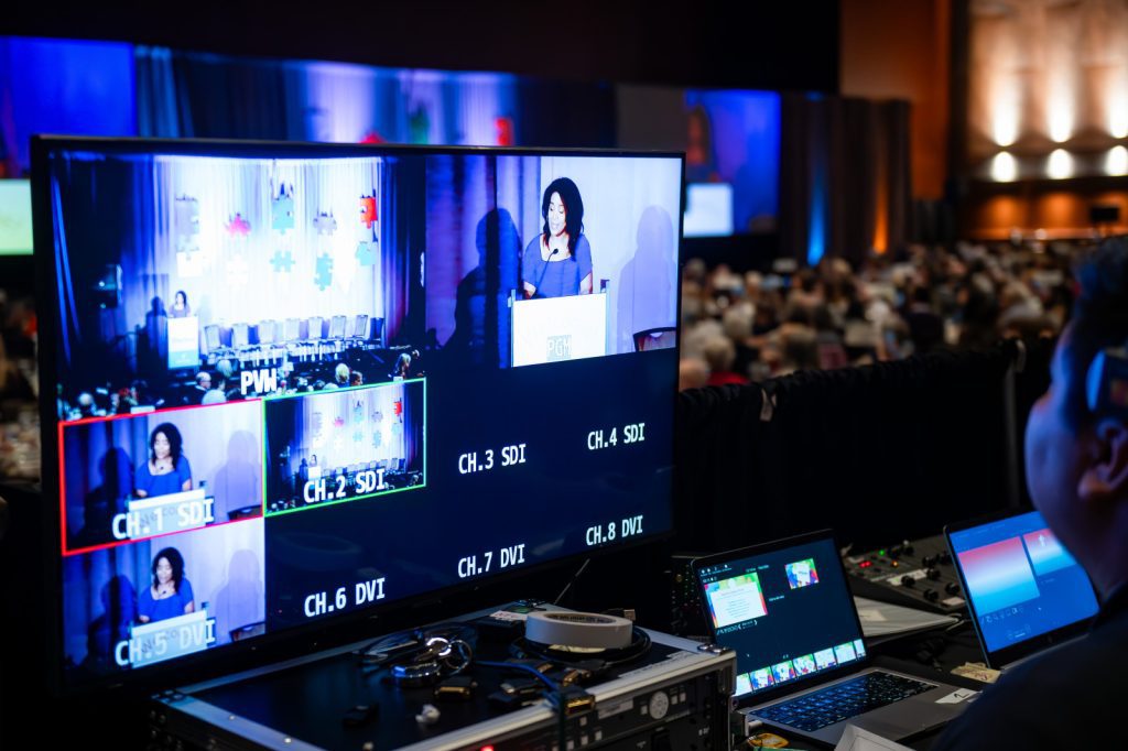 An AV tech looks at their monitors which display multiple camera angles and feeds.