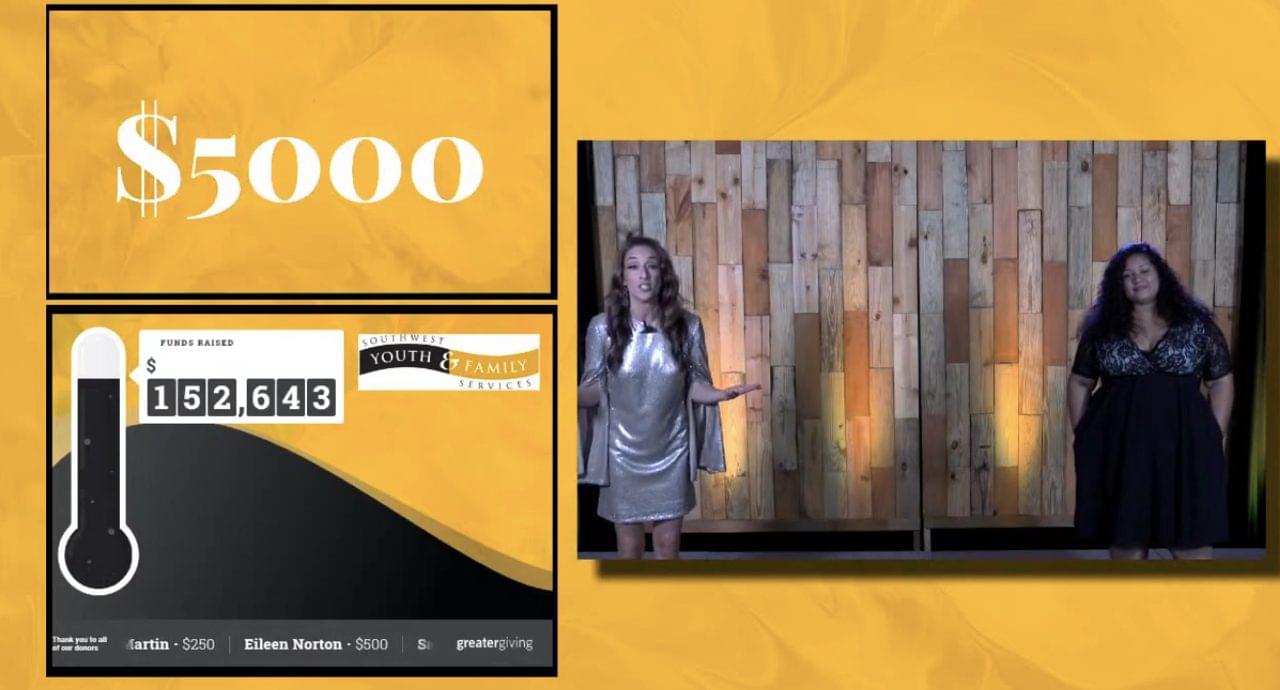 Two women stand on stage beside a wooden backdrop at the Southwest Youth & Family Services record-breaking fundraiser. Next to them, a screen displays $5,000, a fundraising total of $152,643, and donor names with their contribution amounts.
