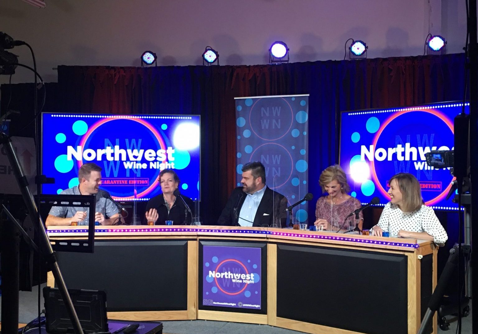 Five people sit at a panel desk with "Northwest Wine Night" screens and banners behind them, engaged in a lively event discussion under studio lighting, captured live in the Livestream Studio.