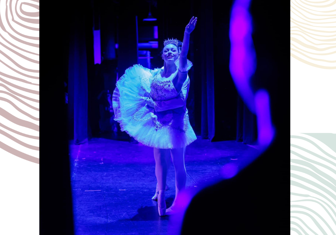 A ballerina moves on stage with blue lights